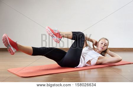 Young fit woman works out in the fitness class. Exercises for the abs. Space for placing text.