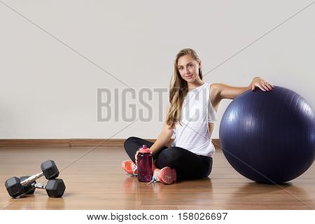 Young fit woman relaxes after training near gymnastic ball. The concept of well-being, health and fitness.