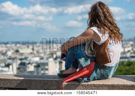 Paris, France- June 30, 2013: Girl Seating On A Low Wall Watching Monuments Of Paris From The Top Of