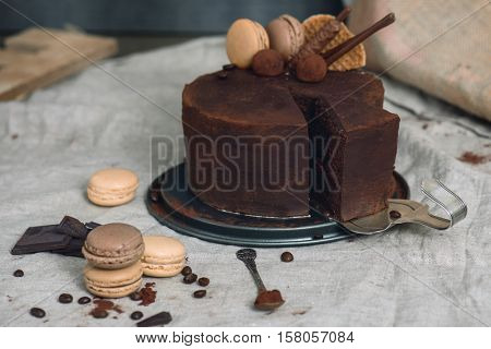 Chocolate cake covered with cocoa powder, one slice on a vintage silver cake server. French macarons and chocolate around