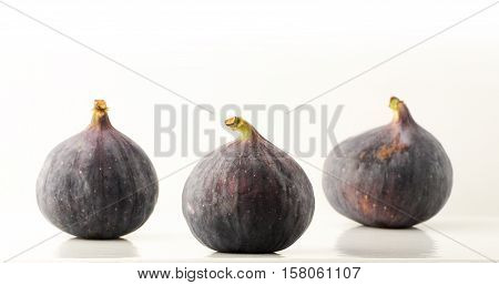 three ripe fruit fig closeup on a light background with reflection