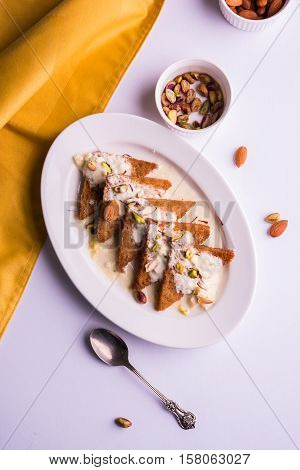 Shahi Tukda prepared - deep fried bread in ghee, garnish with sweetened cream and dry fruits. Indian sweet dish