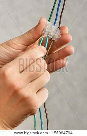 hands of electrician connecting wires in terminal block clamps