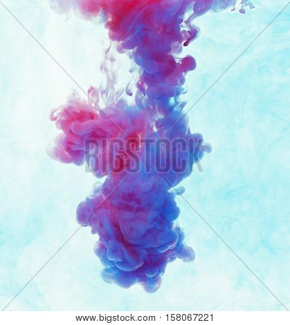 Color drop underwater creating a silk drapery. Ink swirling underwater. Cloud of colorful ink. Blue and magenta mix into violet