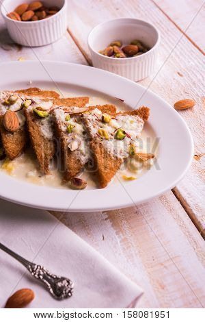Shahi tukda prepared - deep fried bread in ghee, garnish with sweetened cream and dry fruits.