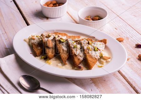 Shahi tukda prepared - deep fried bread in ghee, garnish with sweetened cream and dry fruits.