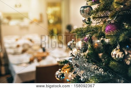 Closeup of tinsel and decorations hanging from the branches of a Christmas tree in a home during the festive season