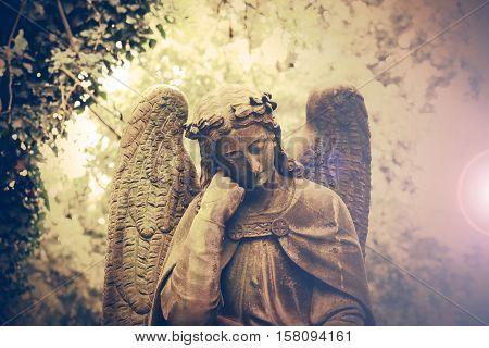 Statue of a beautiful angel. Olsany Cemetery, the largest graveyard in Prague, Czech Republic. Summer time with moody, dark sepia colors