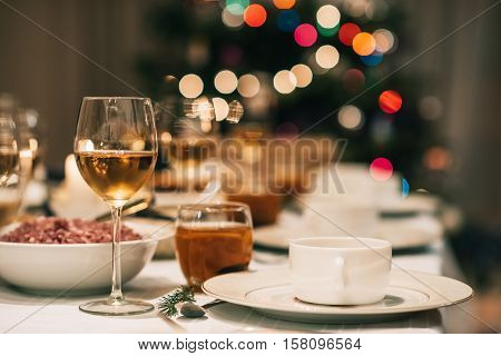 Dining table full of a variety of delicious festive food and wine with a Christmas tree in the background