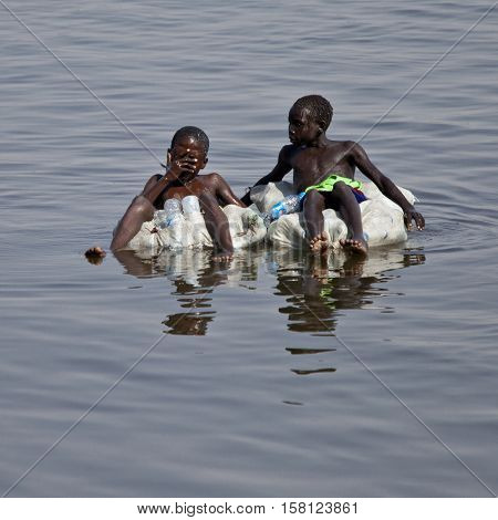 JUBA, SOUTH SUDAN-FEBRUARY 19, 2013: Unidentified kids float down the Nile river on sacks filled with empty water bottles.