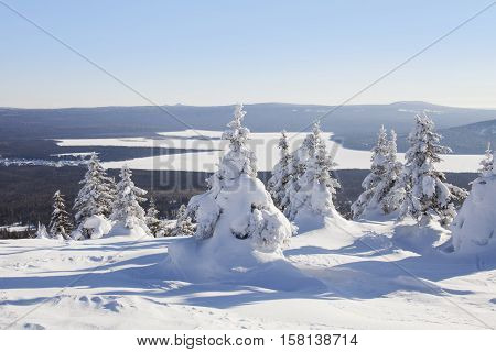 View of the lake from mountain range Zyuratkul winter landscape. Snow swept spruces