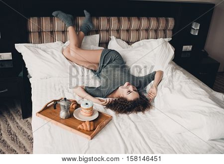 Beautiful young girl 20-24 year old lying with breakfast in bed. Good morning.