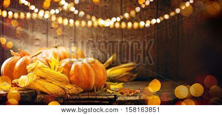 Happy Thanksgiving Day background, wooden table decorated with Pumpkins, Corncob, Candles and autumn leaves garland. Beautiful Holiday Autumn festival concept scene Fall, Harvest