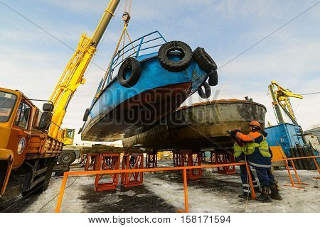 MOSCOW, RUSSIA - NOVEMBER 11, 2016: State Unitary Enterprise Mosvodostok performs recovery vessels on coastal winter parking. Workers attach a ship to the metal supports.