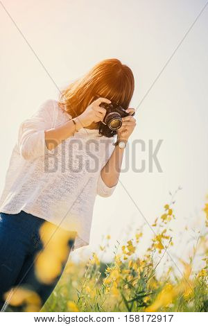 Young woman with camera in the Sunhemp garden sunset