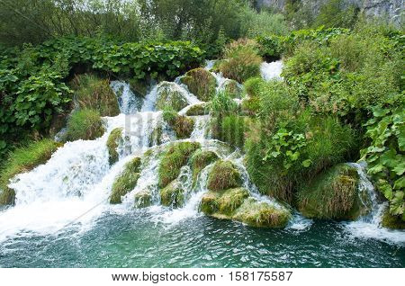 Cascade waterfall on the end of the Kaluderovac lake. Flow of water among green grass. Plitvice lakes national park Croatia