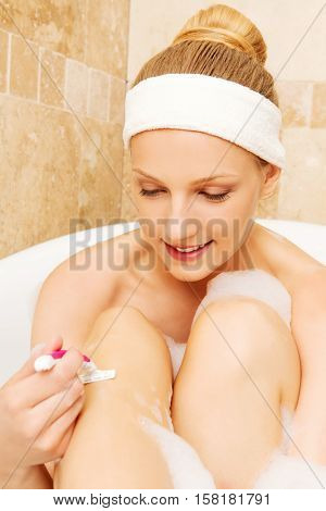 Young caucasian woman shaving legs