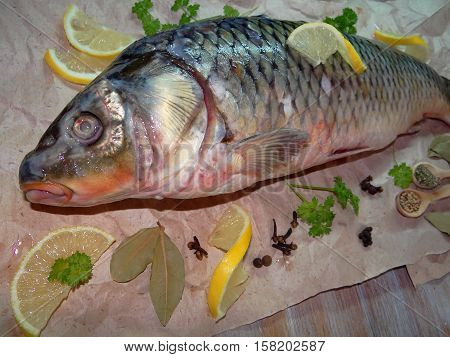 fish carp lies on paper with spices and lemon