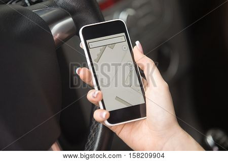 Close-up of traveler female hand holding her phone with navigation map on the screen, trying to scope out her car route
