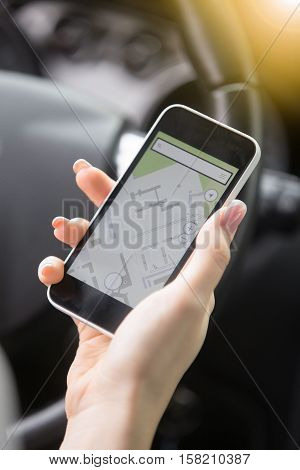 Close up of traveler female hand holding her smart phone. Young woman traveling by car using GPS instead of a paper map, to see destination, checking travel time and distance for available route
