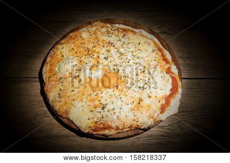 Cheese Italian pizza with a whole egg yolk in the middle served on a wooden plate in dark