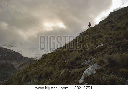Hiker gazing at the glacier in the glacial valley in the desolate peruvian mountain landscape