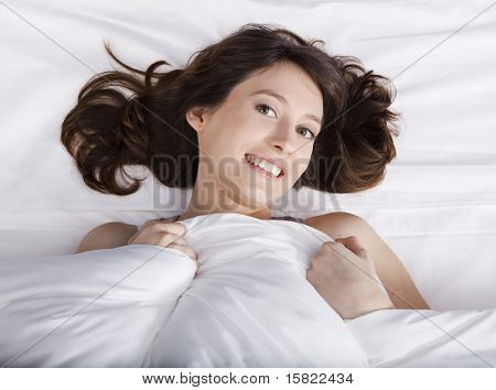 Porttrait de uma jovem bonita e natural na cama