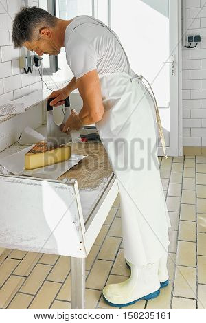 Cheese Maker Cutting Gruyere De Comte Cheese At The Dairy