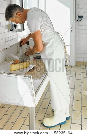 Cheese Maker Cutting Gruyere De Comte Cheese In The Dairy