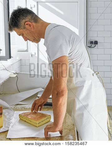 Cheese Maker Wrapping Morbier Cheese At Dairy