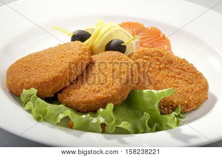Cooked cutlets on a plate served with fresh herbs and olives