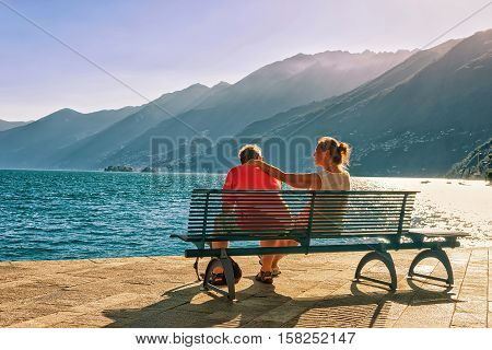Ascona Switzerland - August 23 2016: Romantic couple sitting on the bench at the promenade of the luxurious resort in Ascona on Lake Maggiore Ticino canton in Switzerland.