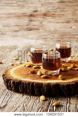 Italian liqueur Amaretto in cups with almonds on a wooden table, selective focus