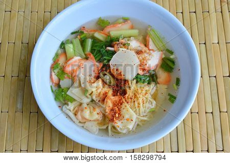 Chinese egg noodle with barbecue pork and dumpling in clear soup dressing chili on bowl