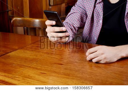 Portrait of young latin man using his smartphone at a cafe. Indoors.