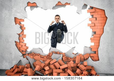 Businessman ruins a brick wall with his leg isolated on the white background. Decisive actions. Brandnew business ideas. Destruction of impediments.