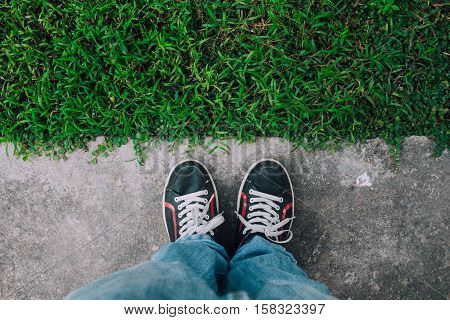 Feet on the cement floor and grass for waiting and determine