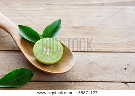 Lemons with green leaf in spoon on wooden background