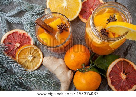 Winter healing ginger drink with lemon honey and oranges. Cinnamon star anise fir twigs tangerines dried grapefruit. Winter christmas background top view. Love for a healthy raw food concept.