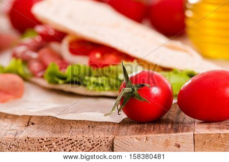 Piadina with ham and lettuce on wooden table.