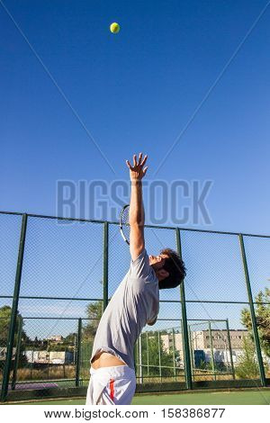 Professional tennis player is doing a kick tennis on a tennis court on a sunny summer morning. He is dressed in sportswear.