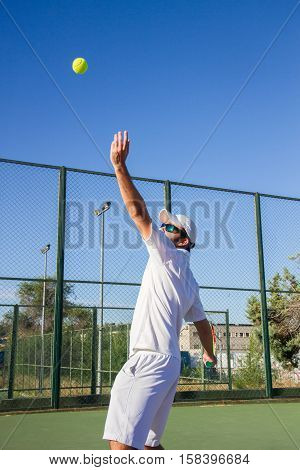 Professional tennis player is doing a kick tennis on a tennis court on a sunny summer morning. He is dressed in sportswear.