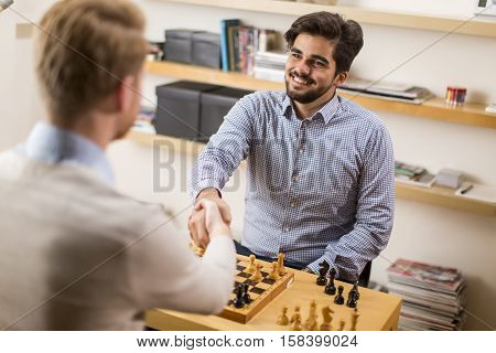 Two young men playing chess in room