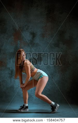 Attractive girl dancing twerk iat the blue studio background