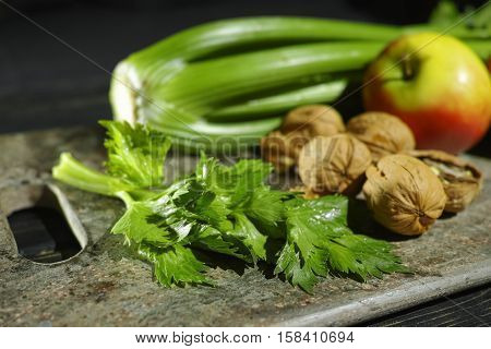 Ingredients for Waldorf salad - celery apples walnuts - fresh and healthy vegetables on granite board.