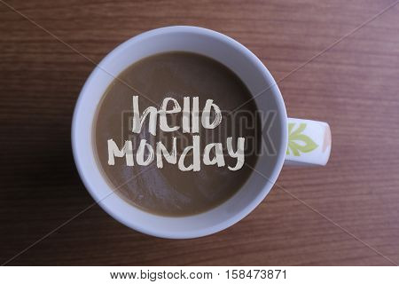 Hello monday./ Inscription hello monday in a cup of coffee and wooden background