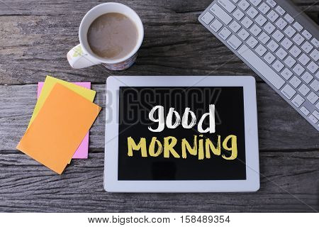 Tablet pc with good morning and a cup of coffee on wooden background