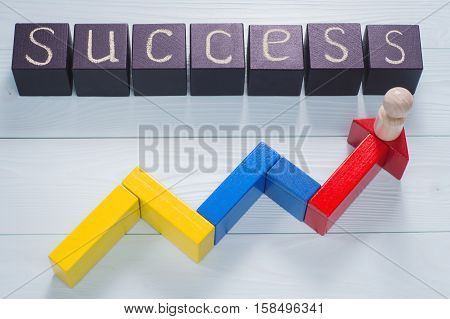 The word success written on a black wooden cubes and an arrow of colored blocks pointing upwards. Arrow sign pointing up with success word. Person climbing stairs with arrow