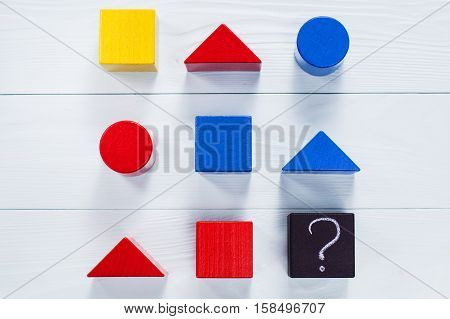 IQ test. Choose correct answer. Logical tasks composed of geometric wooden shapes. Children's educational logical task flat lay.