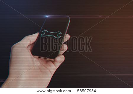 Close up of man hand holding smartphone with Wrench Icon on Light Motion Background and Lens Flare - Digital 3d Effect Style Color